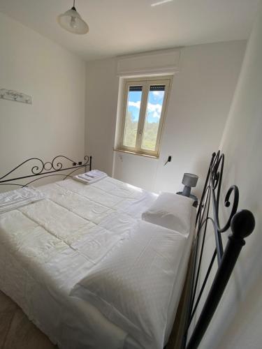 a bedroom with a bed with white sheets and a window at Villa Laurus in Torre dell'Orso
