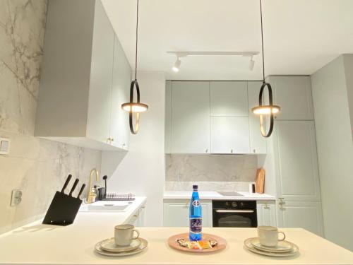a kitchen with white cabinets and a bottle of water on a table at Apartament Środowa 6 by Prestige Home in Szczecin