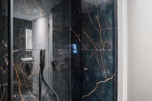 d'une douche avec des murs en marbre noir et une porte en verre. dans l'établissement Luxury Modern Duplex With Sea View, à Herzliya Pituah