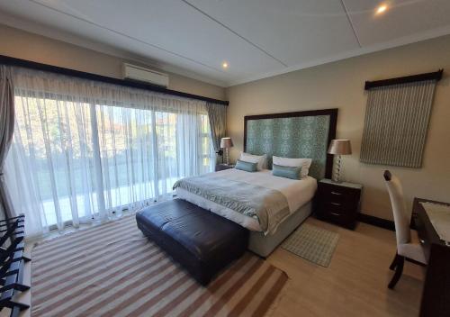 a bedroom with a bed and a desk and large windows at Zimbali KJ01 4 Bedroom Home in Ballito