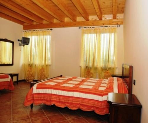 a bedroom with a bed and two windows at Agriturismo Parco Del Chiese in bedizzol