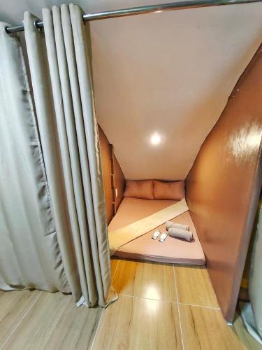 uma pequena cama num quarto minúsculo com cortinas em Aashvi Cozy Cabin Hostel near Mactan Airport em Pusok