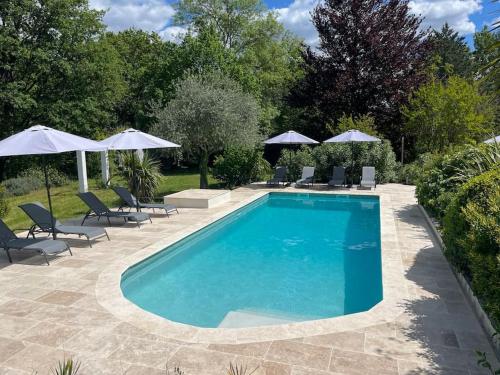 une piscine avec chaises et parasols dans l'établissement Maison Moutas, au Thoronet