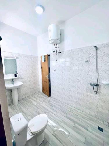 ein Bad mit einem WC, einem Waschbecken und einer Dusche in der Unterkunft Villa Pékin-kirikou in Cotonou