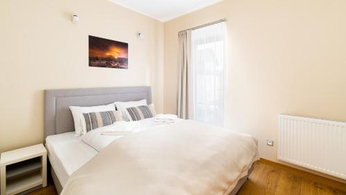 a bedroom with a white bed and a window at Wonder Home - Apartament Kremowa Pianka - blisko szlaków turystycznych, wyciągów, aquaparku i Kościoła Wang in Karpacz