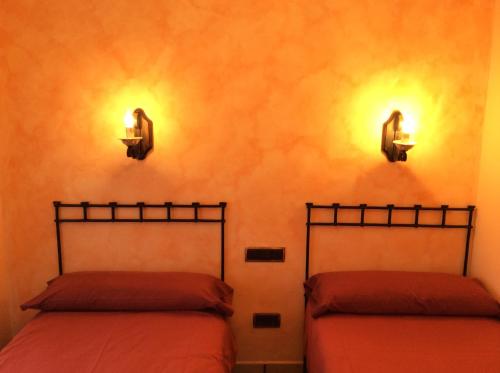 Casa Rural Sierra Vicor في Sediles: سريرين في غرفة مع أضواء على الحائط