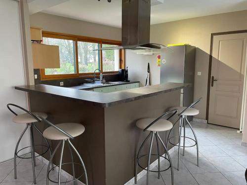 une cuisine avec trois tabourets de bar et un comptoir dans l'établissement Grande maison à louer pour les 24h et autres dates, au Mans