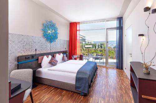 a bedroom with a bed and a large window at Sedartis Swiss Quality Hotel in Thalwil