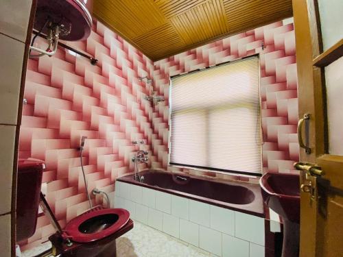 un bagno rosa con servizi igienici e lavandino di Lamzy parimahal. a Srinagar