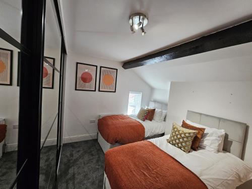 a bedroom with two beds with orange and white at Oxton Apartments - JCS Property 10 minutes from Central Liverpool in Upton