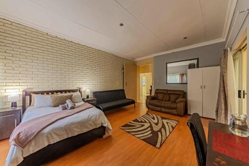 a bedroom with a bed and a couch and a chair at Homely Haven in Roodepoort