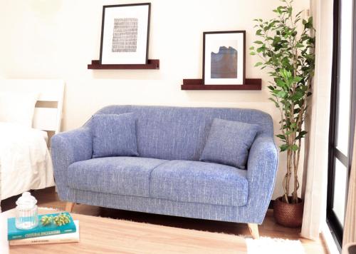 un sofá azul sentado en una sala de estar en Maihama Ushio Lodge 潮ロッヂ Room 101 en Urayasu