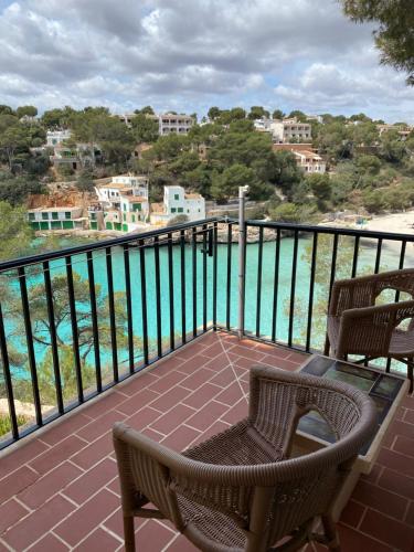 balcón con sillas y vistas al agua en Hostal Palmaria en Cala Santanyi