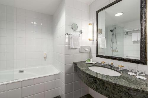 y baño con lavabo, bañera y espejo. en NH Brussels Carrefour de L’Europe, en Bruselas