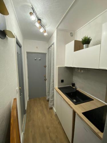 une cuisine avec des armoires blanches et un évier dans l'établissement Studio Cosy Centre Port residence calme avec wifi, au Cap d'Agde