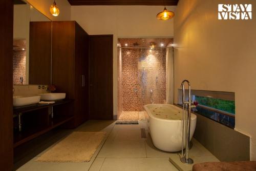ein Badezimmer mit zwei Waschbecken, einer Badewanne und einer Dusche in der Unterkunft StayVista's Del Lago Farms - Lakeview Villa with Infinity Pool, Projector & Indoor-Outdoor Games in Nashik
