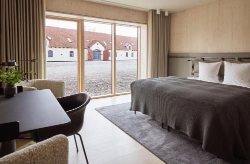 a bedroom with a bed and a desk and a window at Aggersvold Gods in Jyderup