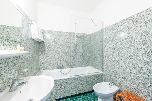 a bathroom with a tub and a sink and a toilet at Hotel Atlantico in Lugano