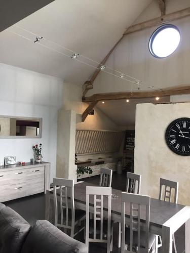 une salle à manger avec une table, des chaises et une horloge dans l'établissement Le Breuil, à Amboise