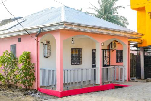 a small pink house with a tin roof at Maison Meublée *WIFI* *CLIM* *PARKING* in Douala