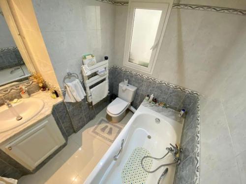 een badkamer met een bad, een toilet en een wastafel bij The Epitome of Luxury: S+2 Apart & Parking Ennasr2 in Ariana
