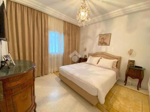 een slaapkamer met een groot bed en een kroonluchter bij The Epitome of Luxury: S+2 Apart & Parking Ennasr2 in Ariana