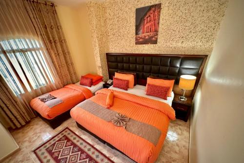 a bedroom with two beds with orange sheets at Anbat Midtown Hotel in Wadi Musa