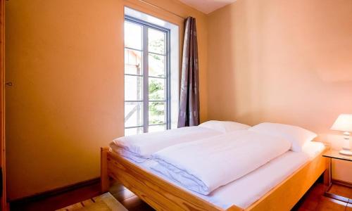 uma cama num quarto com uma janela em Haus zu den Büschen 02 em Wustrow