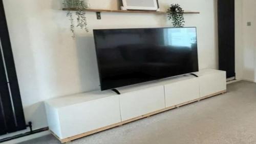 uma grande televisão de ecrã plano sentada num centro de entretenimento branco em Volmarsteiner Apartment Dortmund em Dortmund