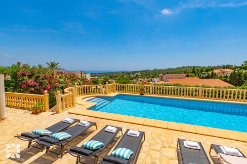a swimming pool with chaise lounges and a swimming poolvisor at Villa Perla by Abahana Villas in Teulada