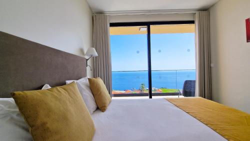 a bedroom with a bed with a view of the ocean at Eden Sun - A Modern Luxury Villa with a Panoramic View in Prazeres
