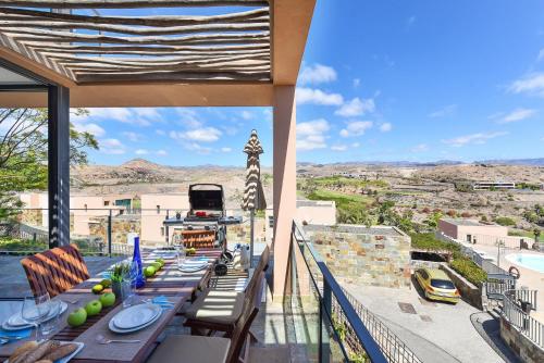 a balcony with tables and chairs and a view of a city at Los Lagos 36 by VillaGranCanaria in Las Palmas de Gran Canaria