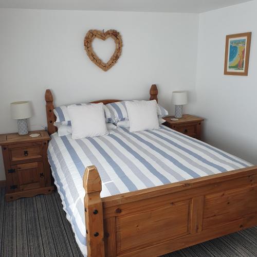 a bedroom with a wooden bed with a heart on the wall at Chynoweth Mews in Newquay