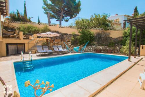 a swimming pool with chairs and an umbrella at Villa Paradise by Abahana Villas in Calpe
