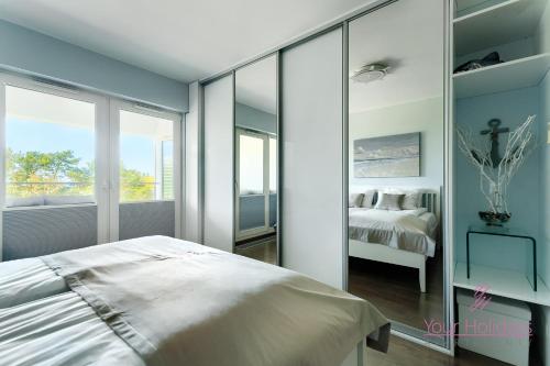 a bedroom with a bed and a mirrored wall at Your Holidays Playa Baltis in Międzyzdroje