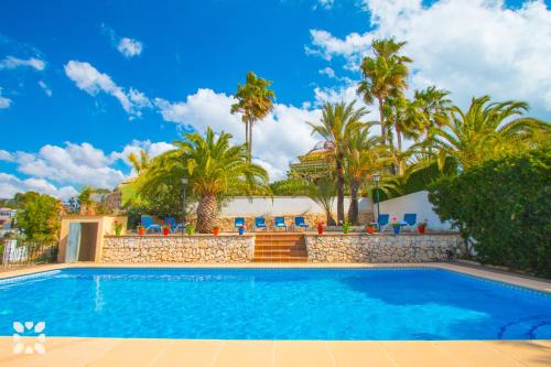 una piscina en un complejo con palmeras en Villa Paula by Abahana Villas, en Benissa