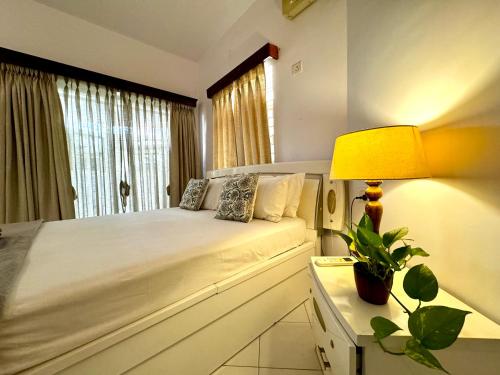 a bedroom with a bed with a lamp and a window at La- Maria's By The Beach Goa in Benaulim