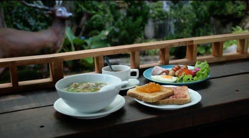 una mesa con un tazón de sopa y un plato de comida en U Maerim Chiangmai - อยู่แม่ริม เชียงใหม่ en Mae Rim