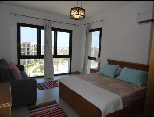 a bedroom with a bed and a couch and windows at Cairo in El Alamein