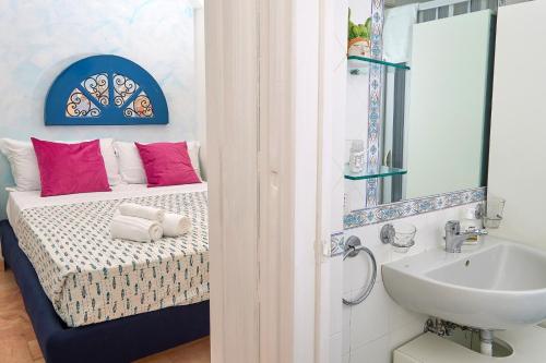 La salle de bains est pourvue d'un lavabo et d'un lit avec des oreillers roses. dans l'établissement Casa Giulia, à Capri