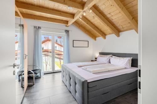 una camera con un grande letto in una stanza con soffitti in legno di Cosy Home Allgäu - modern und gemütlich a Haldenwang