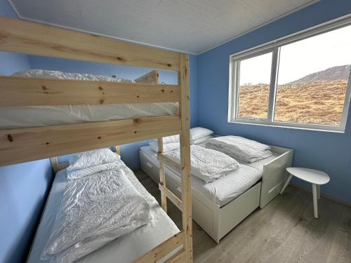 Ce dortoir comprend 2 lits superposés et une fenêtre. dans l'établissement Cabin in Faukás, west part of Iceland - Birta Rentals, à Fossatún