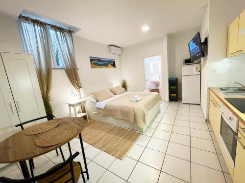 a room with a bed and a table and a kitchen at Basement Studio Bed&Breakfast in Punat