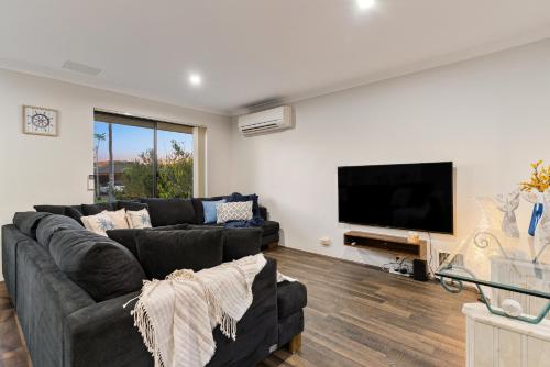 a living room with a couch and a flat screen tv at Sandy Retreat Your Perfect Beach Getaway in Silversands in Mandurah