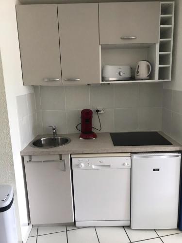 une petite cuisine avec des armoires blanches et un évier dans l'établissement Appartement bord de mer, à Arzon
