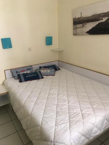 Cette chambre comprend un grand lit blanc avec des oreillers bleus. dans l'établissement Appartement bord de mer, à Arzon