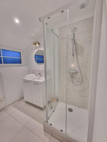 une salle de bain blanche avec une douche et un lavabo dans l'établissement BRISE MARINE DU PRIEURÉ spacieux lumineux à 2 min de la plage, à Dinard