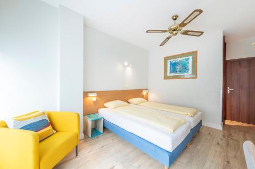 a bedroom with a bed and a yellow chair at Hotel Atlantico in Lugano