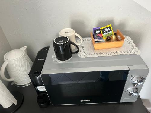 a microwave with a coffee mug on top of it at Šiauliu apartamentai in Šiauliai