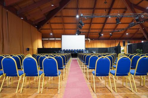 an empty hall with blue chairs and a screen at RHI Porta Bologna in Pieve di Cento